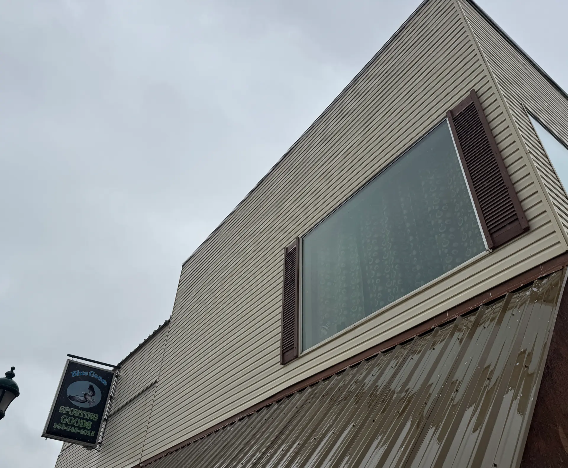 Commercial building with beige lap siding and large windows after exterior washing