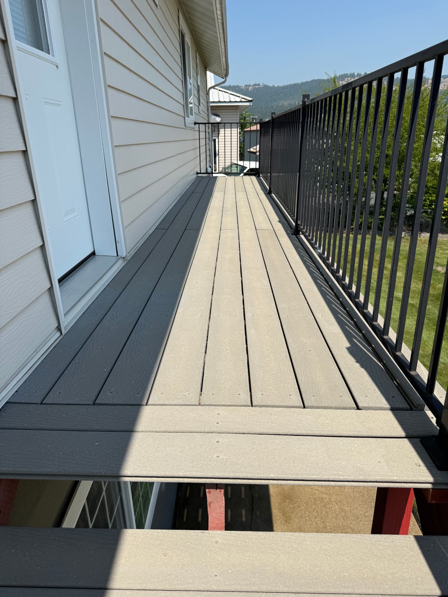 Composite deck boards and black railing cleaned on a hillside home