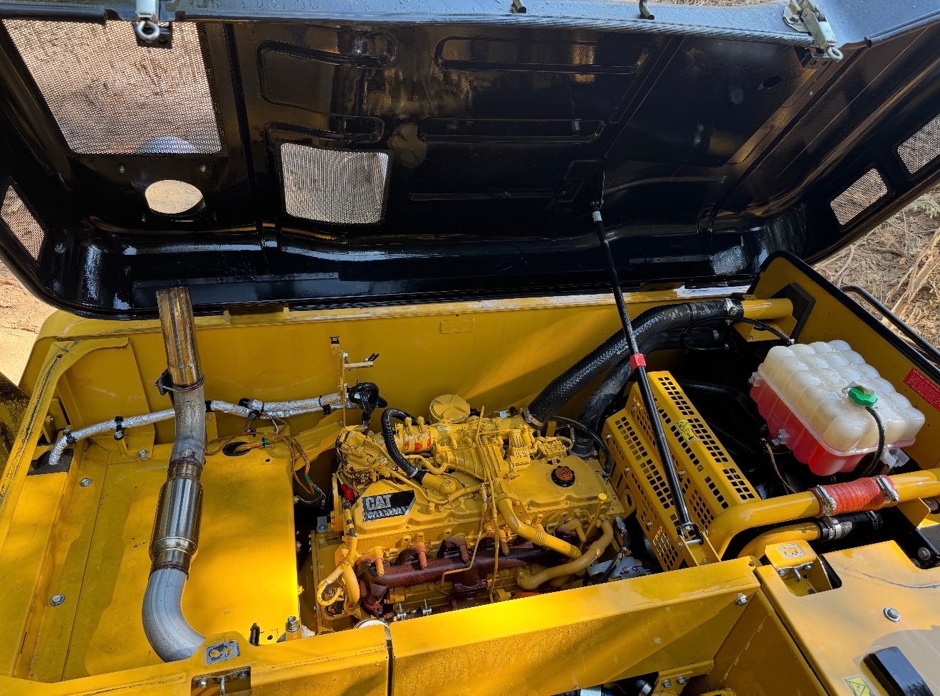 Freshly degreased Cat excavator engine compartment with hood open