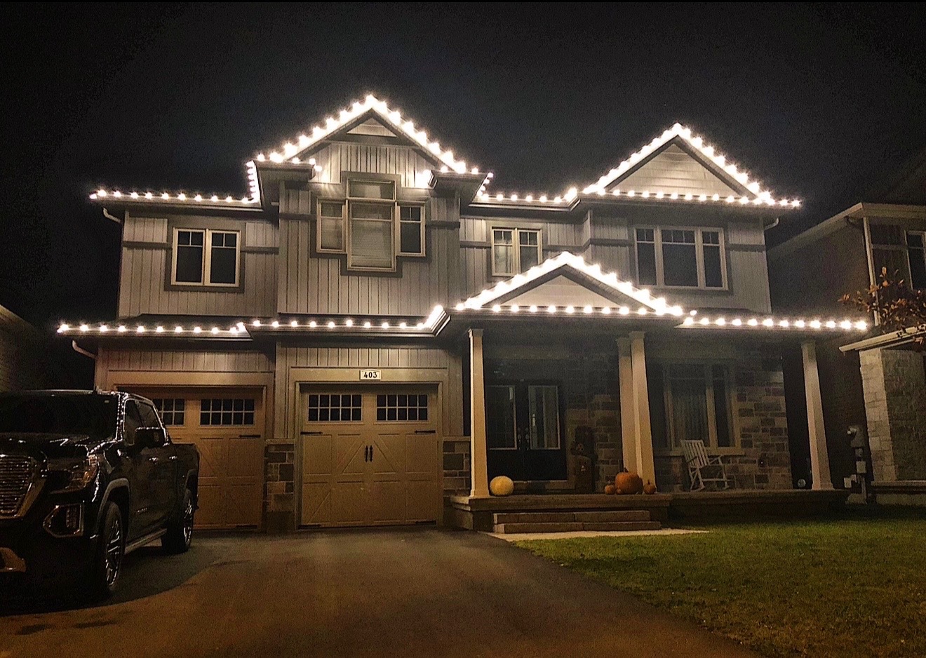 Two-story home outlined in warm white holiday roofline lighting at night (stock image)