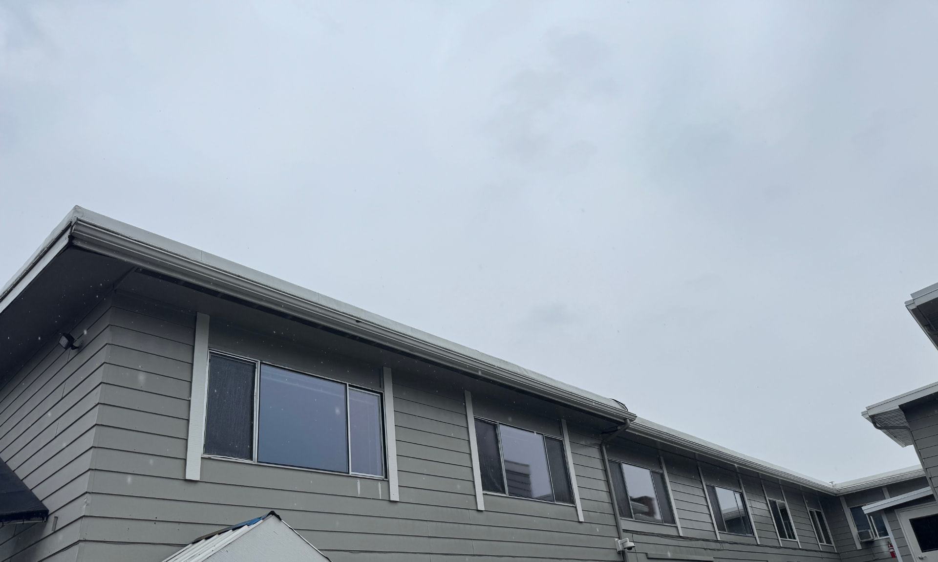 Gray lap siding, white-trimmed windows and gutters cleaned on a two-story home